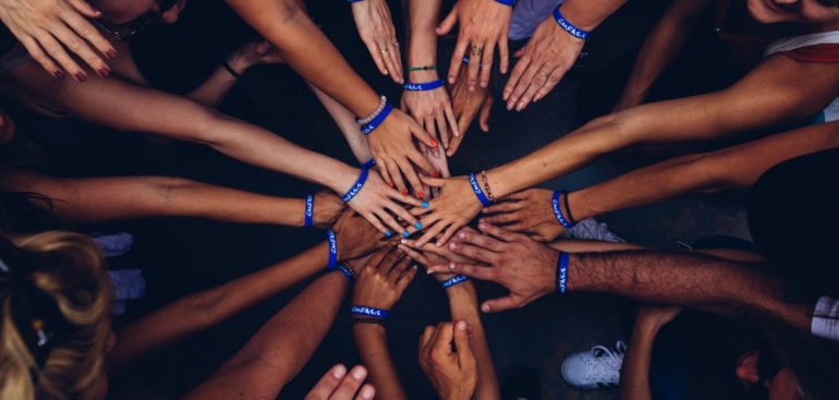Overhead shot of group of people putting hands in the middle of a huddle
